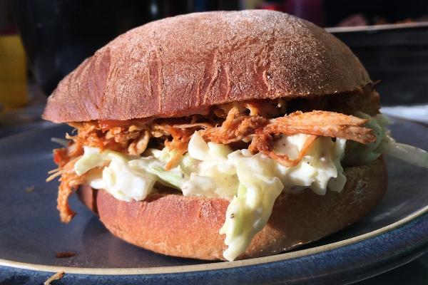 Pulled chicken inside a burger bun with coleslaw and ready to eat.