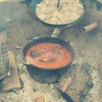 Dutch oven with pulled pork cooking over a campfire