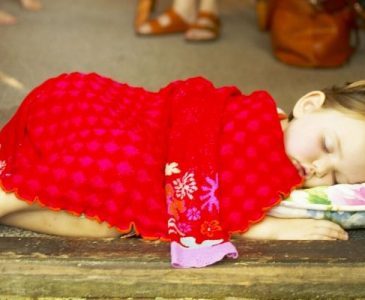 Toddler sleeping on a small matress with a blanket