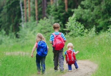 three kids walking on a forest path